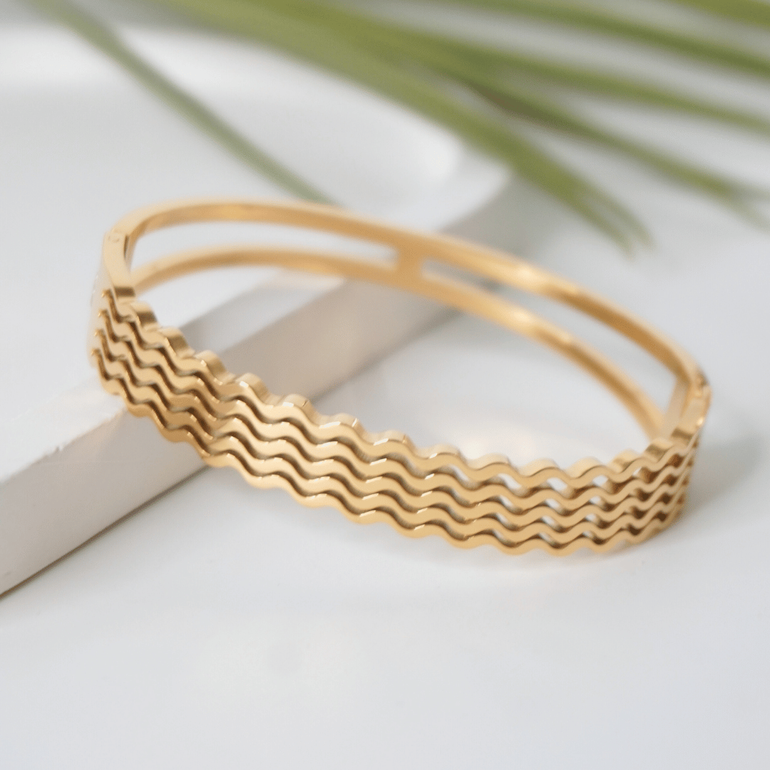 Gold bracelet with wavy pattern on a light background